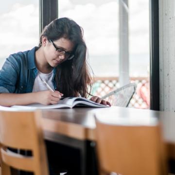 A young woman studiously pores over a workbook.
