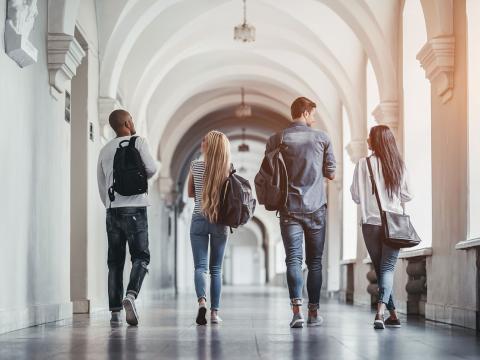 Four college students walking down a hallway.