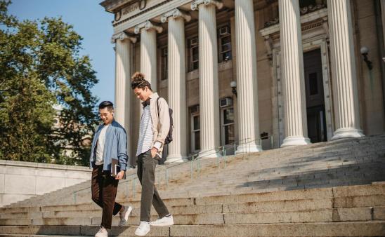 two students walking down the steps of a university building