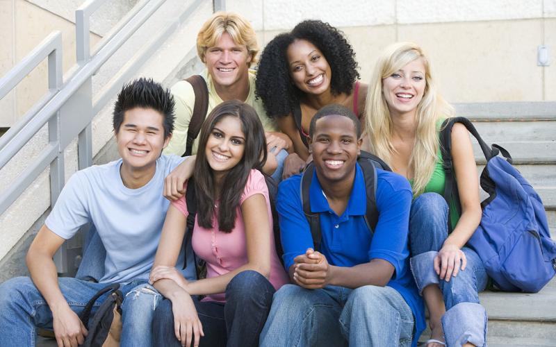 Group of six youth sitting on outdoor stairs looking at the camera.