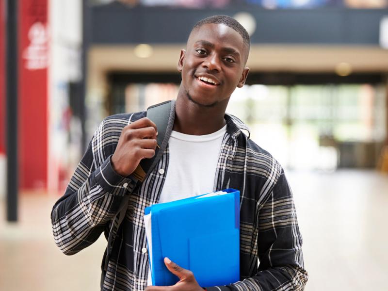 College student holding a backpack and looking at the camera.