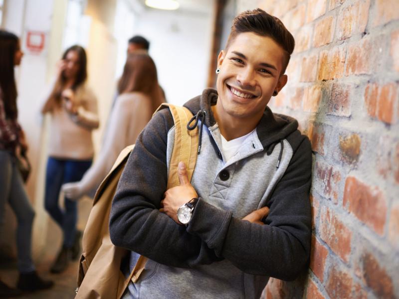 College student leaning against a brick wall.