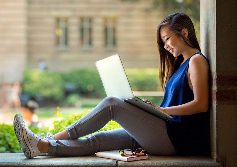 College student sitting in an opening on her laptop.