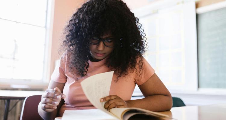 A woman studying a book in an empty classroom